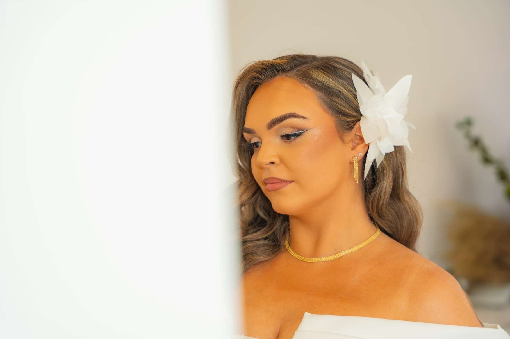 Profil de la mariée pendant les préparatifs, une fleur blanche dans les cheveux