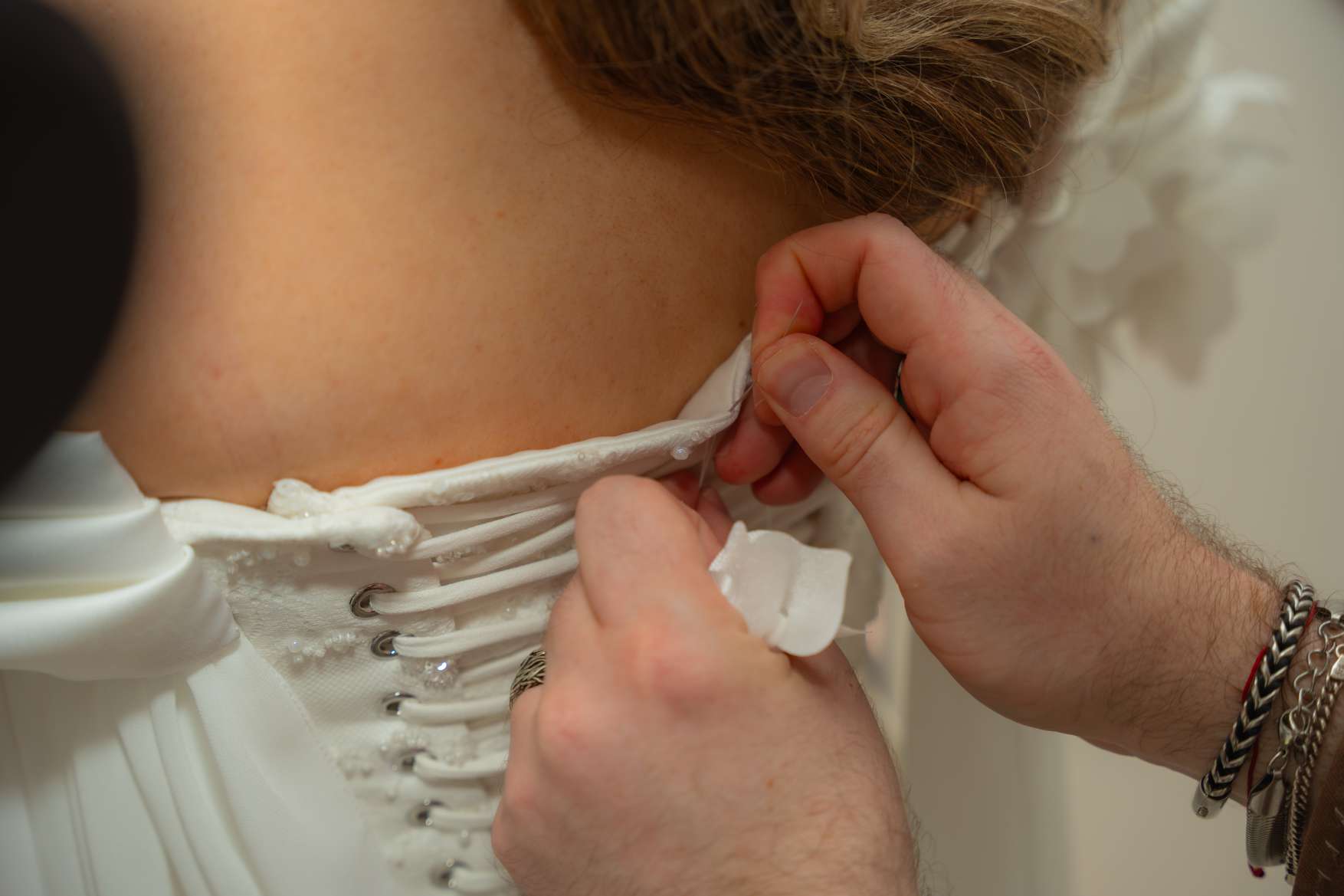 Mains qui lacent le dos de la robe de mariée