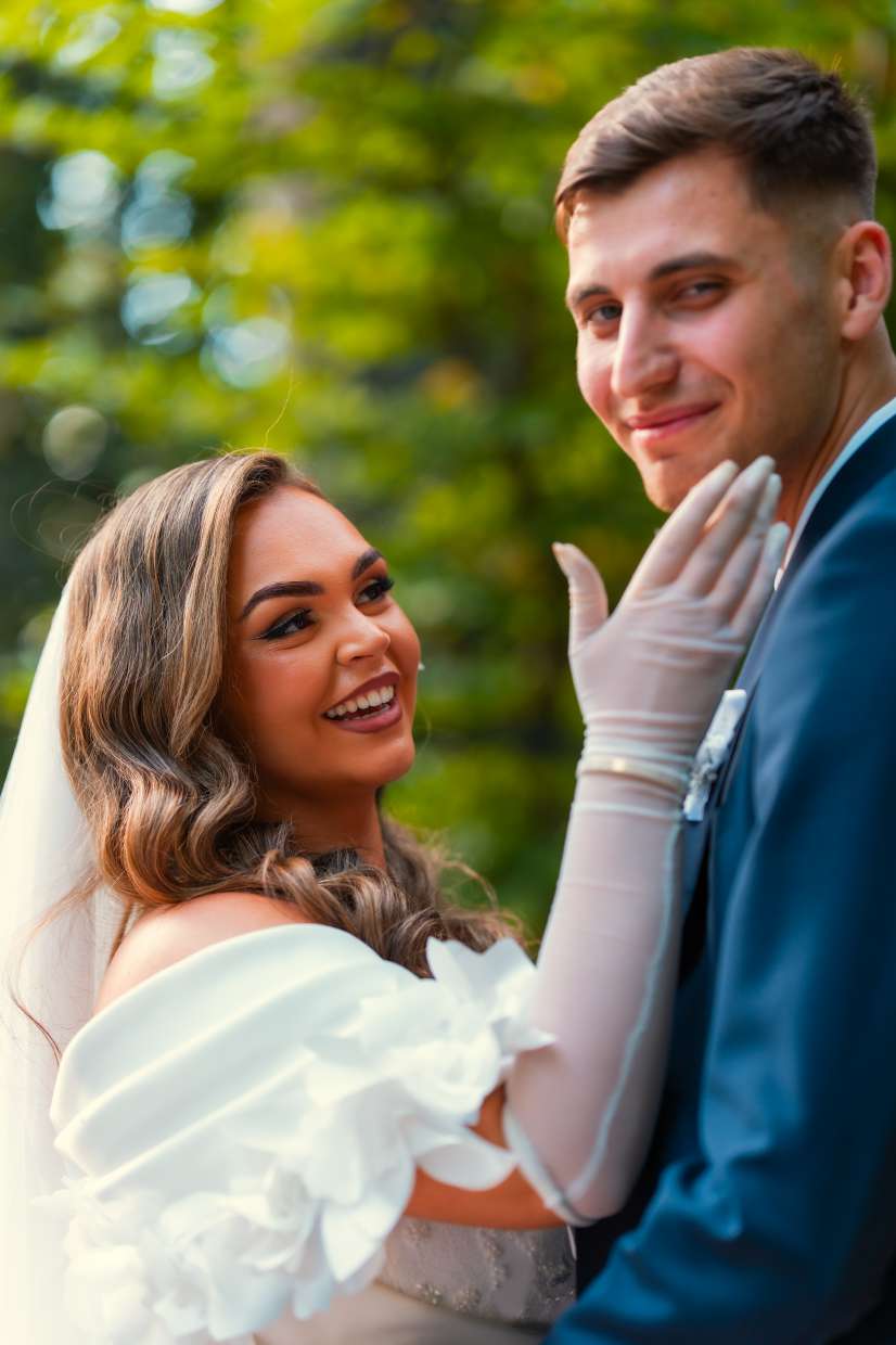 La mariée rit, sa main gantée posée sur la joue du marié