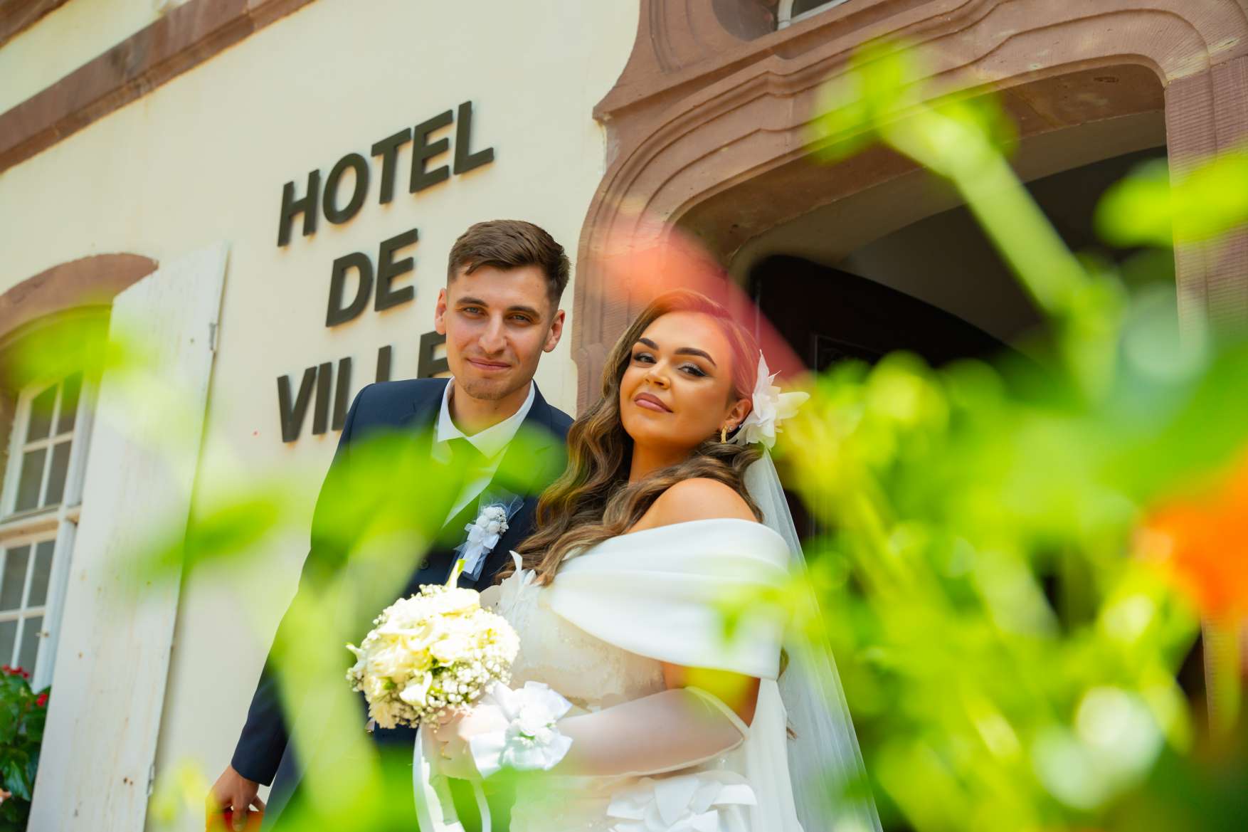 Les mariés devant l’hôtel de ville, vus à travers le feuillage