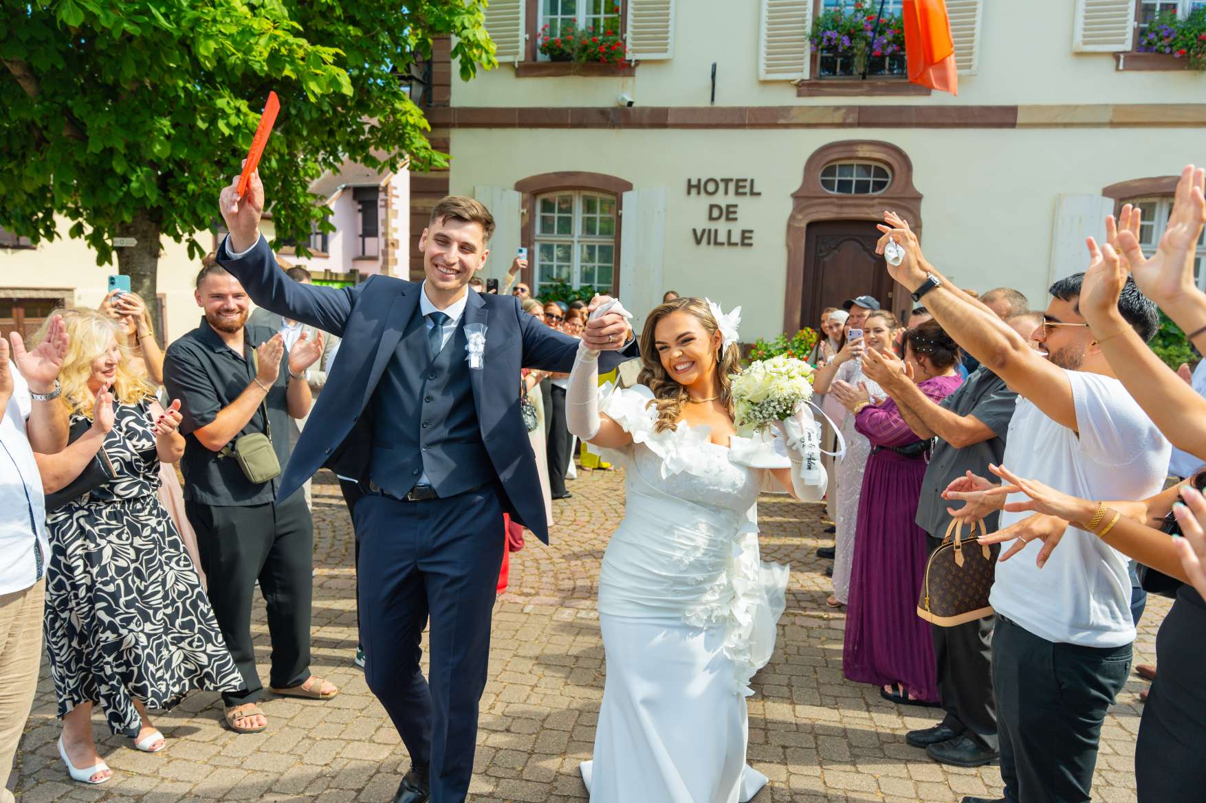 Les invités acclament les mariés à la sortie de la mairie