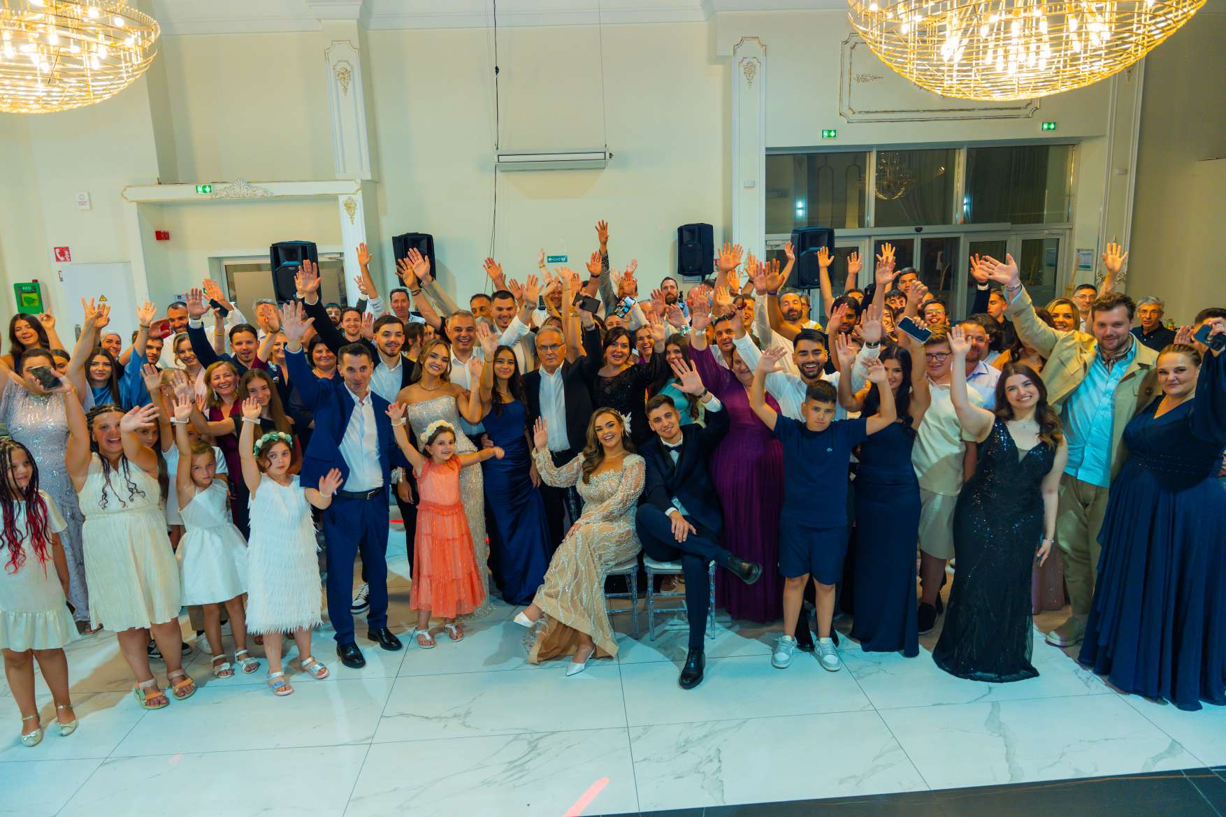 Photo de groupe des invités, bras levés, dans la salle de réception
